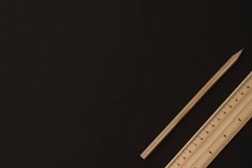 Wooden pencil and ruler on the black background on the right side with blank / empty space