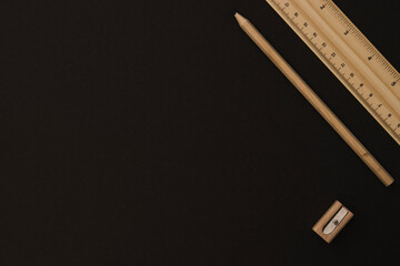 Wooden pencil and ruler on the black background on the right side with blank / empty space
