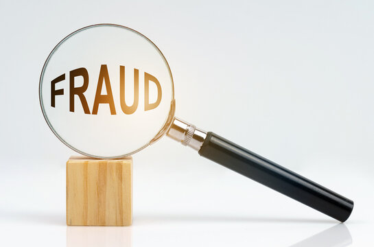 On a white surface there is a cube and a magnifying glass inside which is the inscription - fraud