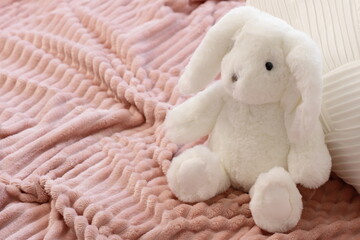 White fluffy bunny toy on pink blanket, lifestyle photo
