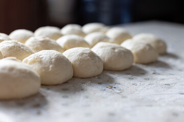 Fototapeta na wymiar Balls from the dough for pies on the kitchen table. Baking at home. Selective focus.
