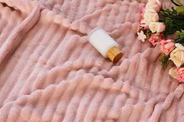 Obraz na płótnie Canvas Cosmetic crystal bottle on pink blanket with flowers, mockup