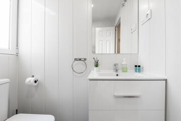 White bathroom with wall mounted frameless mirror, high gloss white wooden cabinet and aluminum window