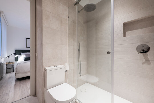 Bathroom with shower cabin with sliding glass screen, niche in the wall and access to a bedroom suite