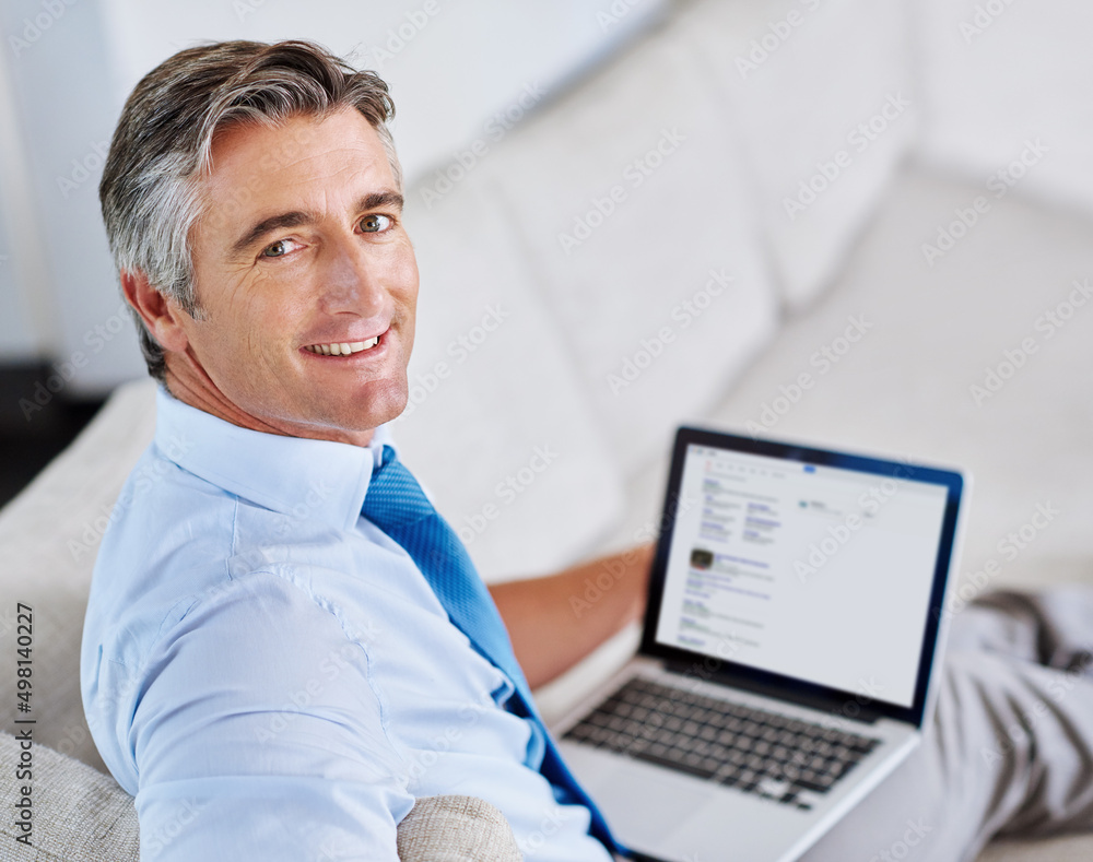 Poster my work is never too far away. portrait of a mature businessman using a laptop while sitting on a so