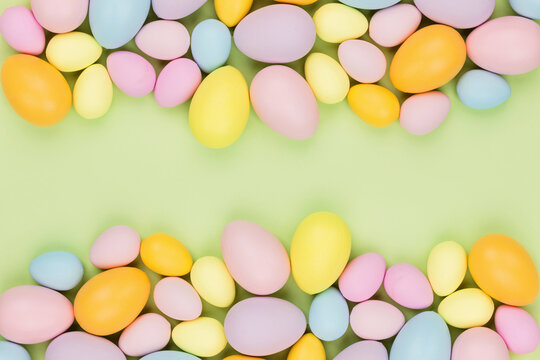 Stylish background with colorful easter eggs isolated on pastel green background with copy space. Flat lay, top view, mockup, overhead, template