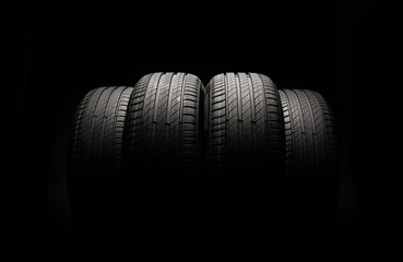 New car tires. Group of road wheels on dark background. Summer Tires with asymmetric tread design. Driving car concept. © bondvit