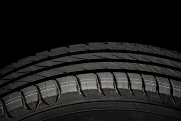 New car tire. Road wheel on dark background. Summer Tire with asymmetric tread design. Driving car concept.