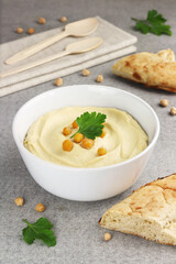 Hummus traditional oriental vegan sauce from chickpea in a white bowl, pieces of bread and spoons. Selective focus