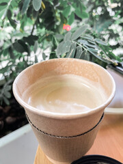 Coffee Cup made of recycled material against green plants, concept of safer and sustainable environment, disposable coffee cup