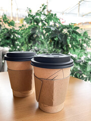 Coffee Cup made of recycled material with Lid against green plants, concept of safer and sustainable environment, disposable coffee cup