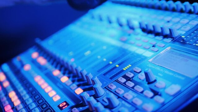 Specialist is operating a mixing consol with a microphone on it