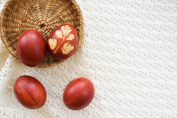 Top view of easter eggs, lying on wicker plate , on a lace tablecloth. Painted brown, with a plant theme. Easter concept.