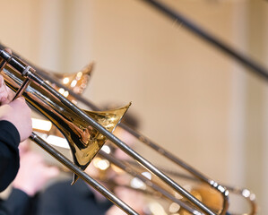 Many people playing the trombone during a performance with their trombone slides being in different positions