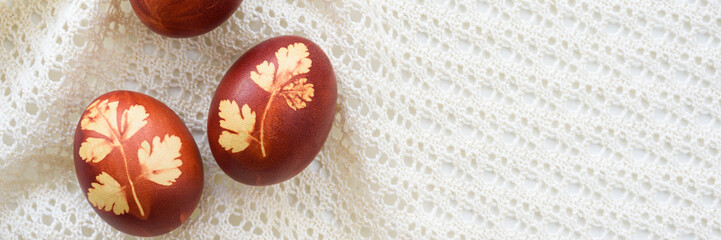 Panoramic photo. Top view of easter eggs, lying on lace tablecloth. Traditional and rustic arrangement. Easter concept.