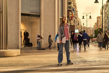 Young woman walking in a zebra crossing with her laptop on the hand