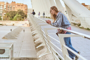 Young woman browsing smartphone on a modern bridge