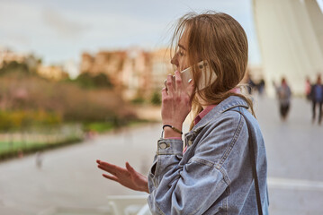 Young white woman talking at her phone on a modern bridge