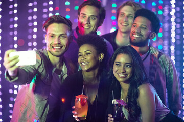 Everybody say cheese. Shot of a happy group of friends taking a selfie with a smartphone in a nightclub.