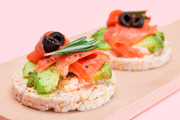 Rice Cake Sandwiches with Fresh Salmon, Avocado and Olives on Wooden Cutting Board. Easy Breakfast. Diet Food. Quick and Healthy Sandwiches. Crispbread with Tasty Filling. Healthy Dietary Snack