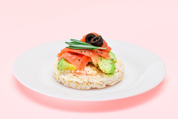 Rice Cake Sandwich with Fresh Salmon, Avocado and Olives on White Plate. Easy Breakfast. Diet Food. Quick and Healthy Sandwiches. Crispbread with Tasty Filling. Healthy Dietary Snack