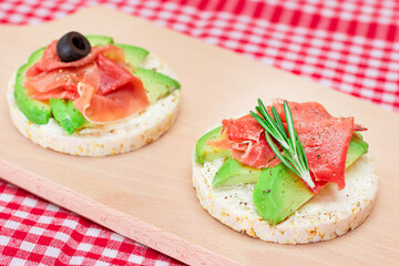 Rice Cake Sandwich with Avocado, Jamon, Olives and Rosemary on Wooden Cutting Board. Easy Breakfast. Quick and Healthy Sandwiches. Crispbread with Tasty Filling. Healthy Dietary Snack