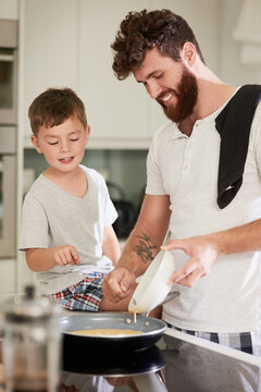 The cutest little soux chef. Shot of an adorable little boy and his father making breakfast together at home.