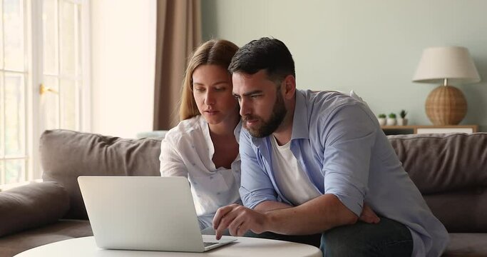 Couple sit on sofa at home use laptop read email, got commercial offer, low price, discount, online lottery, auction victory, feel happy, looks overjoyed. Moment of win, success, achievement concept