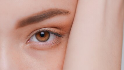 Macro shot of young woman opens her brown eye and looks the camera