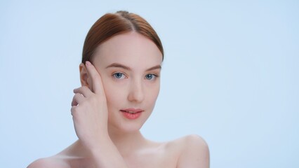 Close-up beauty portrait of young redhead woman softly touches her face sliding fingers to her temple | skin care products commercial footage