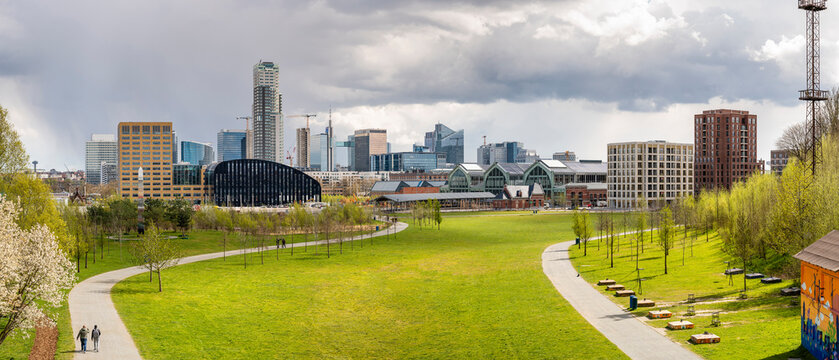 Panoramic cityscape of Brussels city center and economic district with skyscrapers in spring on a sunny day with a dramatic sky and a green park in the foreground