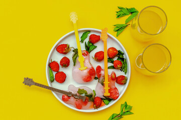 Frozen ice with red strawberry, mint in guitar shape for cold fresh summer lemonade cocktail drinks with orange juice. Homemade sweet fruit berry ice cream popsicles dessert food on gray plate