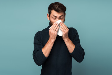 Man sneezing in napkin, cleaning running nose and coughing