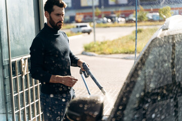 Man smiling to the camera while washing black car