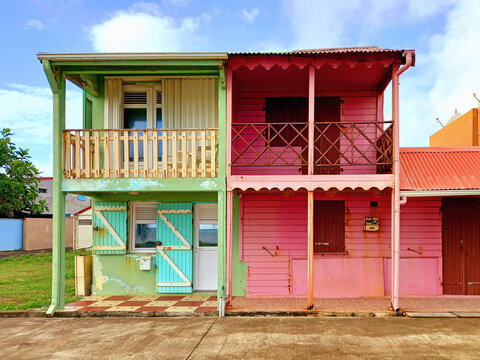 Typical rural Caribbean style houses with pink and green colored walls and headliner, shuttered windows and doors. Tropical architecture and construction.