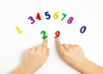 Children's hands move numbers on a white table. Learning colors and to count from zero to ten