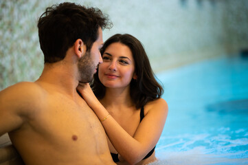Young romantic couple hugging in a swimming pool spa center hotel