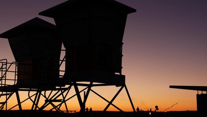 Fototapeta na wymiar Lifeguard stand, hut or house on ocean beach after sunset, California coast, USA. Life guard tower or station silhouette in twilight dusk. Contrast beachfront watchtower for surfing safety on shore.