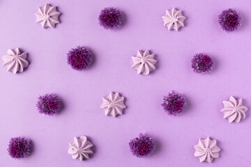 Purple meringue and purple allium flowers on purple background. Food and floral pattern. Flat lay