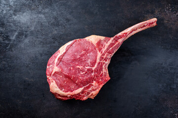 Raw dry aged chianina tomahawk steak offered as top view on an old rustic board with copy space