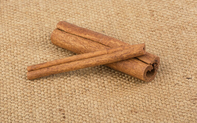 two cinnamon sticks on a burlap background