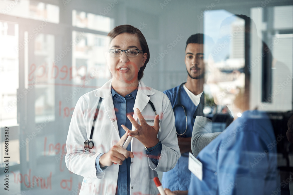 Poster Class is in session. Shot a group of doctors discussing formulas in the office at work.