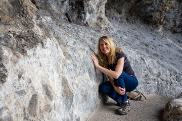 Naklejka na ściany i meble Blonde Woman Hiking Between Rocks on a Cliff Walk