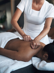 Working out the tension in those pressure points. Shot of a young woman getting a back massage at a spa.