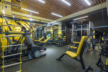 A bright private gym with a variety of sports equipment. Treadmills and equipment for strength exercises.