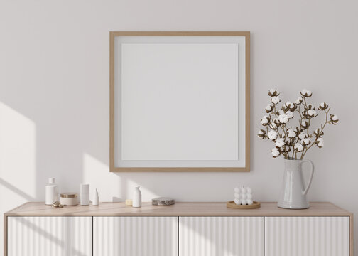 Empty square picture frame on white wall in modern living room. Mock up interior in minimalist, scandinavian style. Free, copy space for picture. Console, cotton plant, vase. 3D rendering.