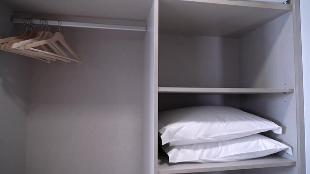 Built-in wardrobe in a hotel with pillow shelves and hangers for tourists close-up.