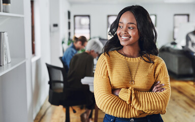 Shes thinking positive thoughts. Cropped shot of an attractive young businesswoman looking thoughtful while standing with her arms folded in the office.