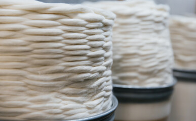 Large round containers with industrial cotton thread twisted in a spiral.