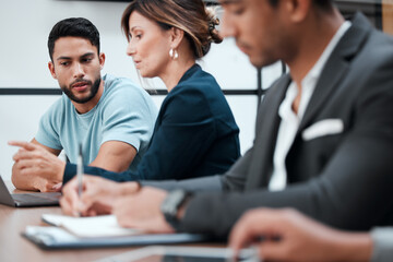 Exchanging ideas and information. Cropped shot of two young businesspeople talking in the boardroom during a meeting with their colleagues.